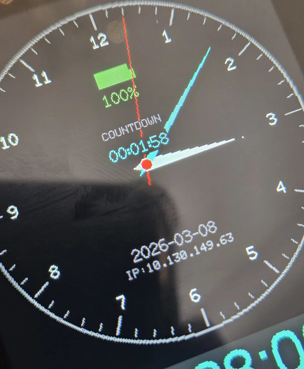 ESP32-S3 smartwatch showing analog watch face with battery level, countdown timer, date, and network address